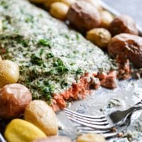 This herb crusted salmon and potato bake is an easy way to get dinner party-worthy meal on the table. A whole salmon filet is topped with a simple, but flavorful lemon-herb sauce and accompanied by crisp baby potatoes!
