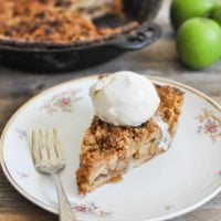 This Paleo apple pie is the REAL DEAL! The perfect, buttery grain-free pie crust comes together with a blend of almond flour, coconut flour, and arrowroot starch, then is filled with apples and finished with a simple crumble topping and coconut whipped cream for the perfect holiday dessert.