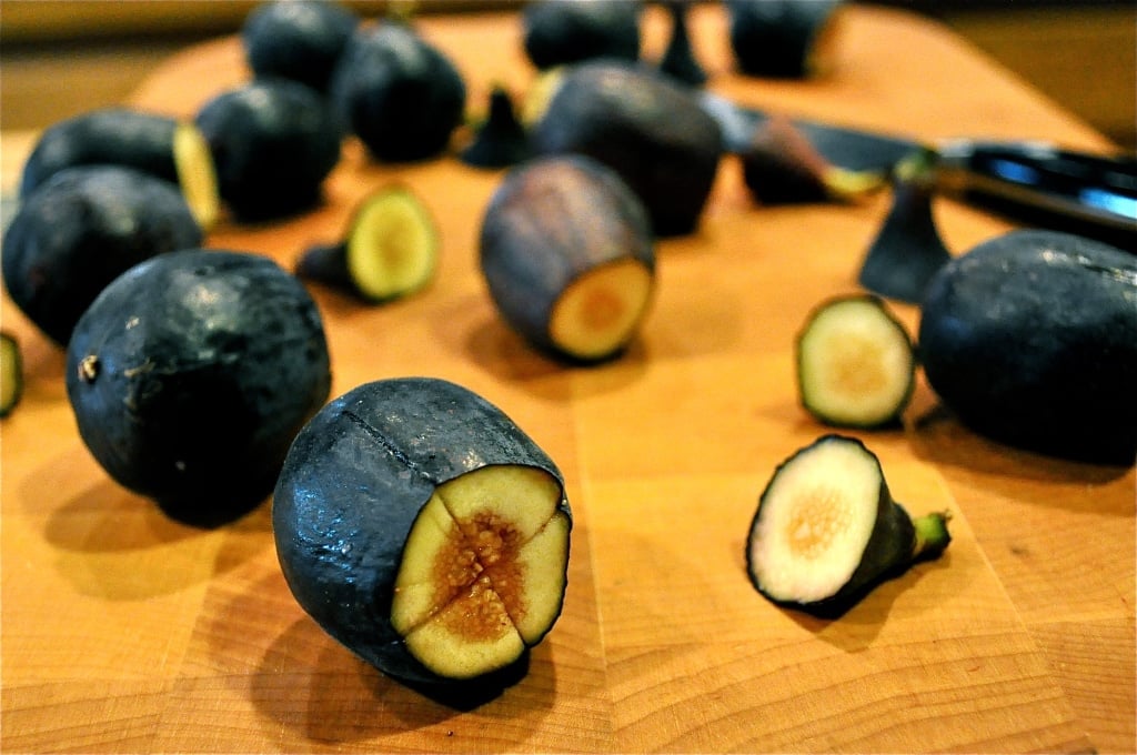 fresh figs on a cutting board with one end cut off and an X cut in the middle