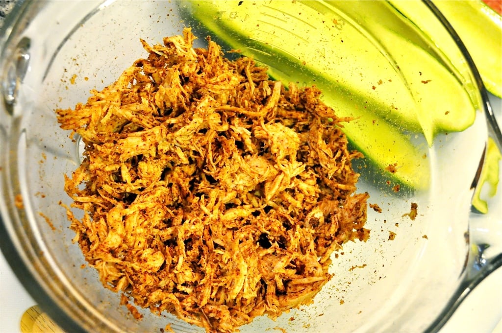 clear glass bowl of mixed shredded chicken and spices