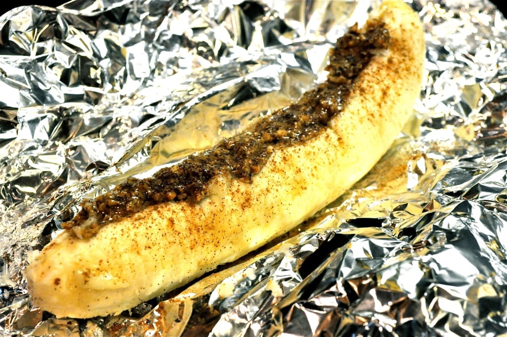 a peeled banana topped with almond butter sitting in foil