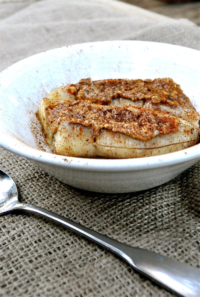 baked bananas in a white bowl topped with almond butter