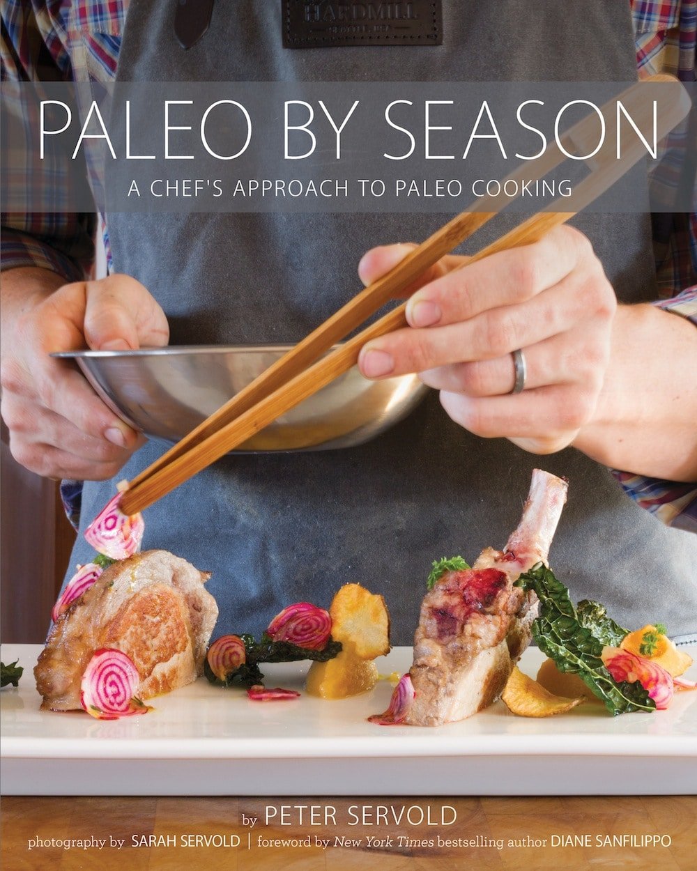 Paleo by Season book cover with an image of a mans hand holding a bowl and a pair of tongs and adding watermelon radishes as a garnish to lamb chops