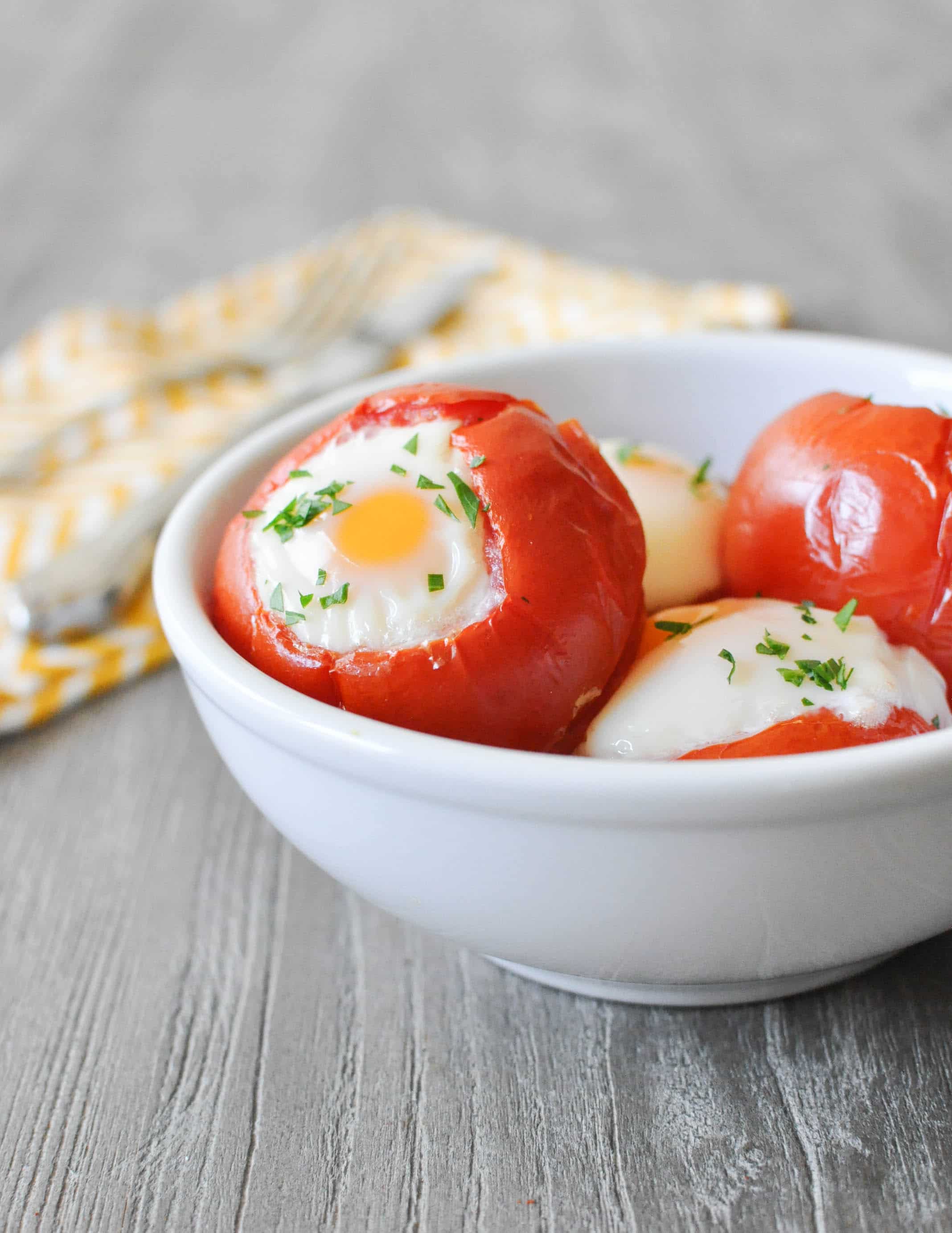 baked tomato eggs in a white bowl on a grey wooden table with a yellow zig zag napkin in the background