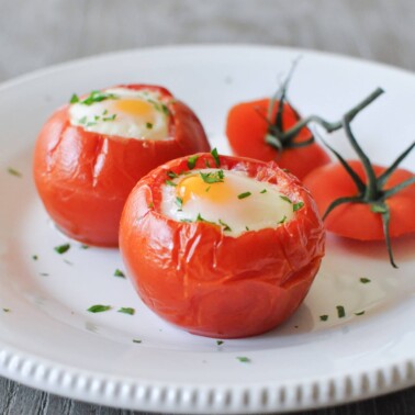 a white plate of two baked tomato eggs