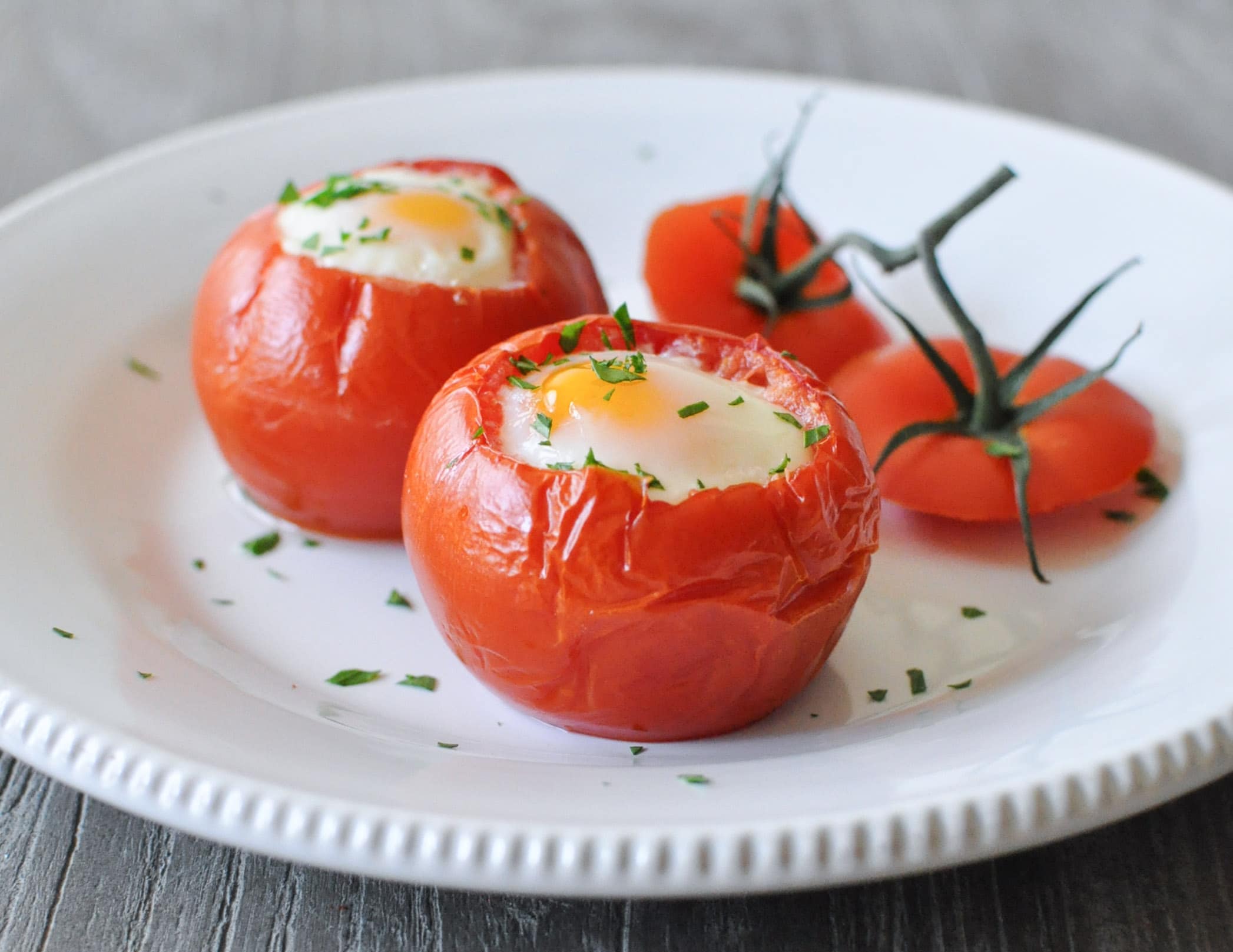 a white plate of two baked tomato eggs