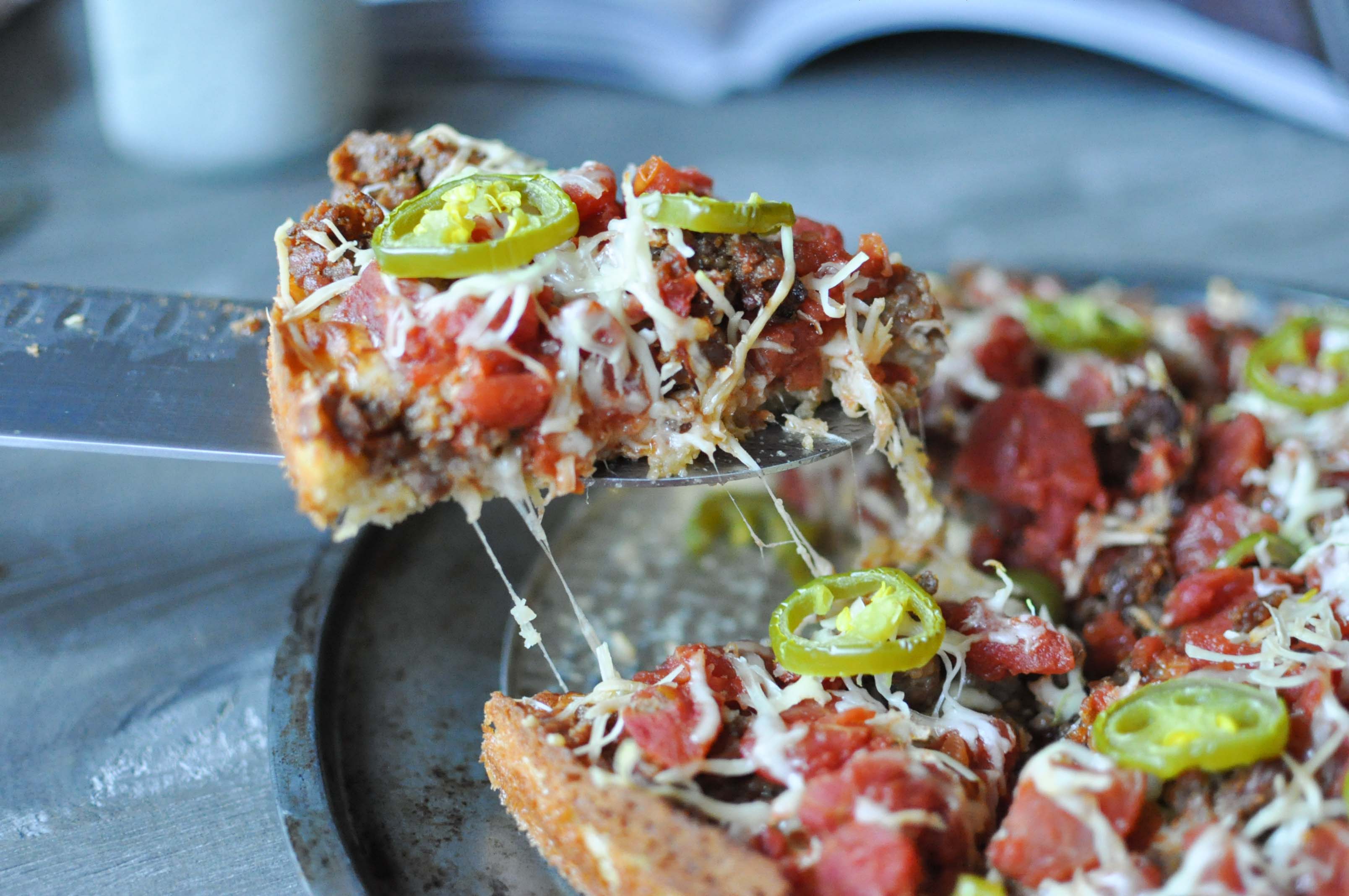 a slice of Chicago deep dish pizza being pulled away from the whole pizza