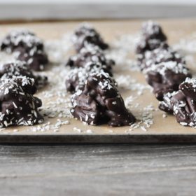 Chocolate Chili Pecan Clusters on a parchment lined baking sheet with coconut flakes on top