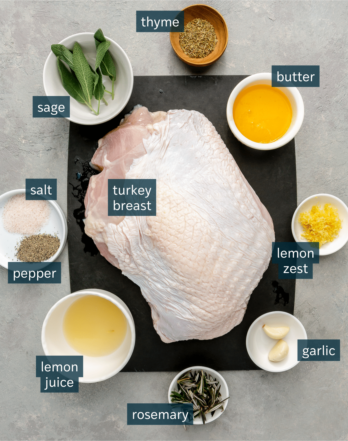 Ingredients for herbed turkey breast sit in a variety of bowls on a grey counter.