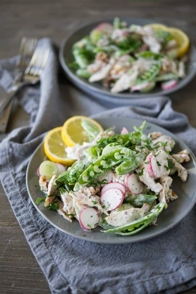 a gray bowl full of chicken salad with snap pea radish slaw on top of a gray napkin