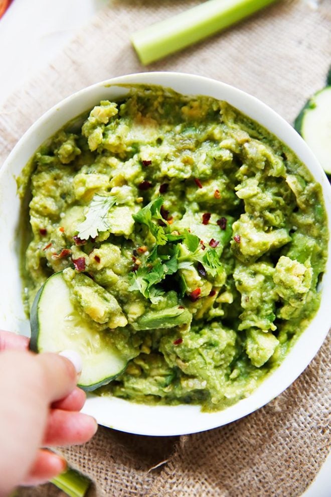 overhead view of a white bowl filled with roasted tomatillo salsa verde guacamole