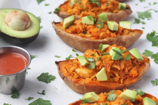 buffalo chicken twice baked sweet potatoes on a white serving platter with avocado on top