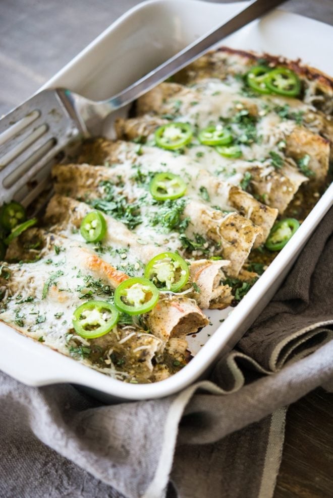 a white casserole dish full of chicken enchilada verde