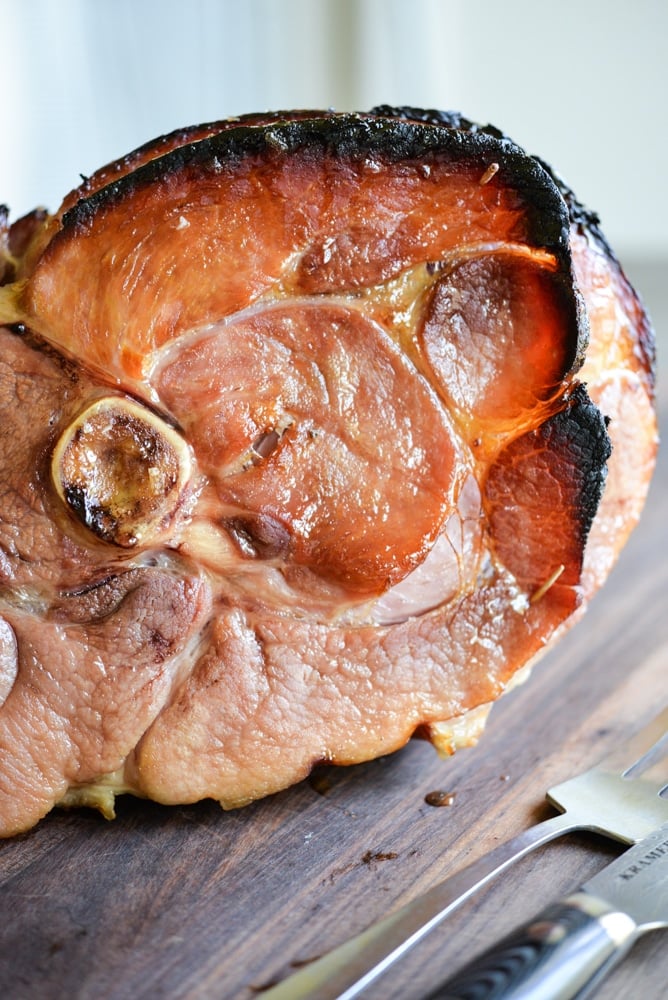 honey glazed ham that is browned around the edges on a wooden surface