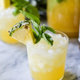 pineapple sangria in a glass with basil leaves as garnish on a marble surface