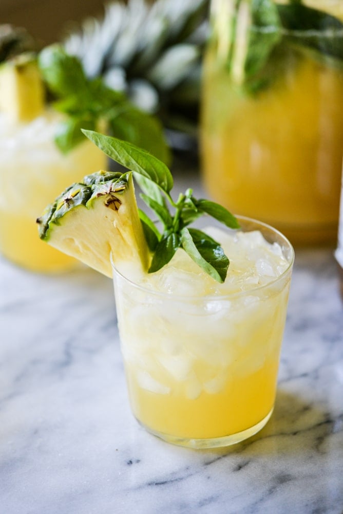 pineapple sangria in a glass with basil leaves as garnish on a marble surface