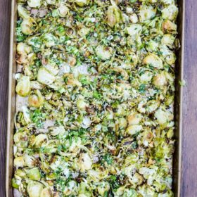 overhead view of a sheet pan of shaved Brussel sprouts on a wood table