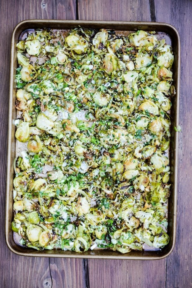 overhead view of a sheet pan of shaved Brussel sprouts on a wood table