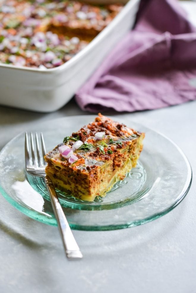 a green glass plate of Chile relleno breakfast casserole with a purple napkin and casserole dish in the background