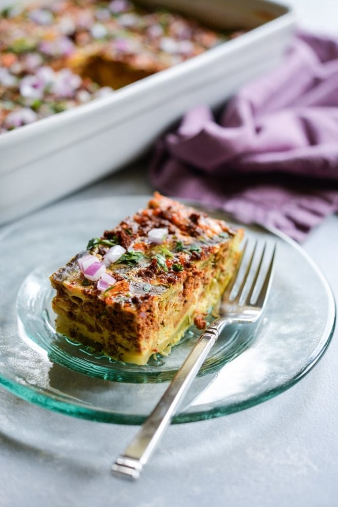 a green glass plate of Chile relleno breakfast casserole with a purple napkin and casserole dish in the background