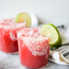 bright pink ginger beet margaritas in a glass with salt on the rim and a circle of lime on a marble surface