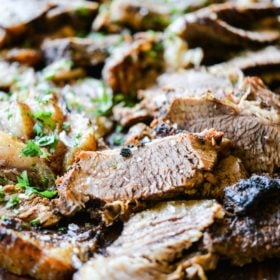 slices of instant pot brisket on a dark wooden cutting board