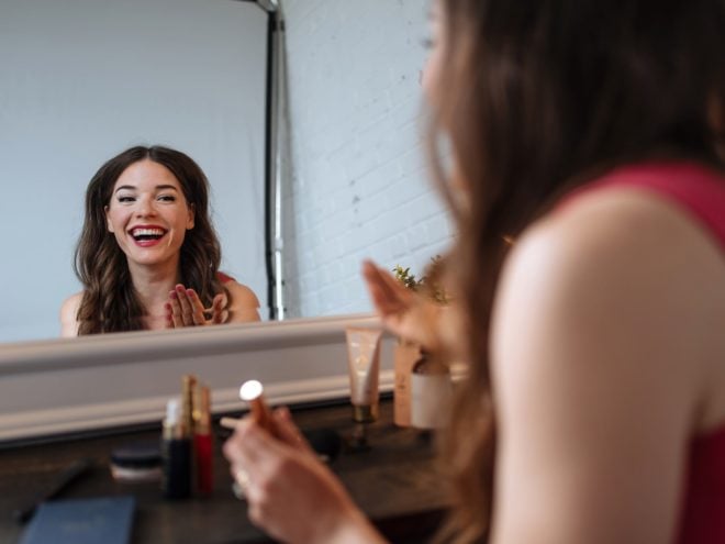 woman applying makeup in the mirror