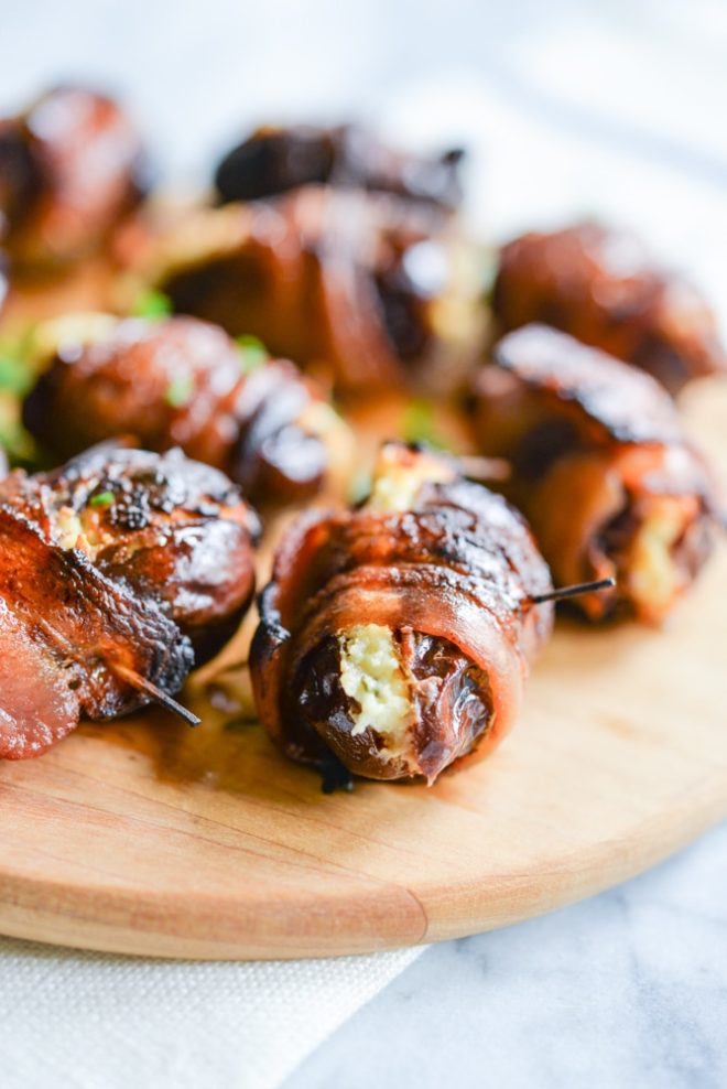 cream cheese bacon dates on a wooden cutting board
