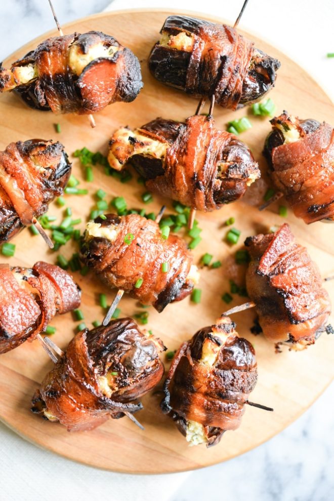 overhead view of cream cheese bacon dates on a wooden cutting board