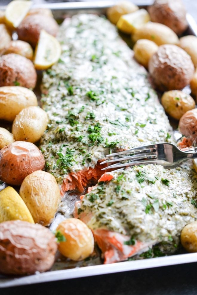 This herb crusted salmon and potato bake is an easy way to get dinner party-worthy meal on the table. A whole salmon filet is topped with a simple, but flavorful lemon-herb sauce and accompanied by crisp baby potatoes!