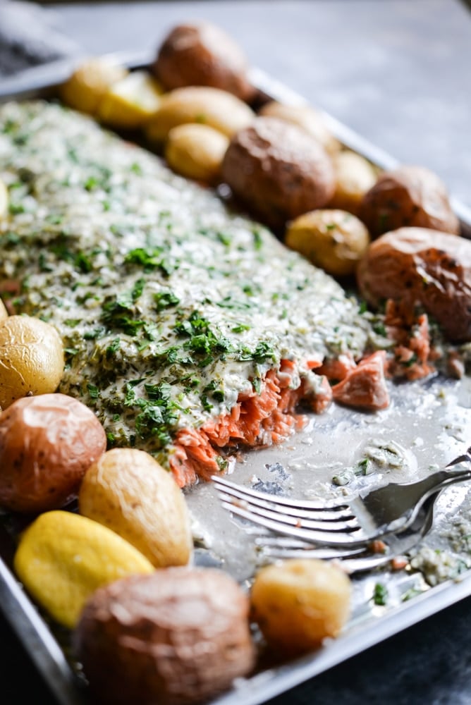 This herb crusted salmon and potato bake is an easy way to get dinner party-worthy meal on the table. A whole salmon filet is topped with a simple, but flavorful lemon-herb sauce and accompanied by crisp baby potatoes!