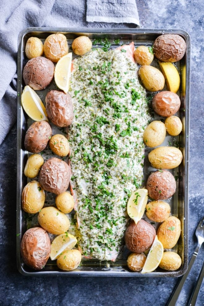 This herb crusted salmon and potato bake is an easy way to get dinner party-worthy meal on the table. A whole salmon filet is topped with a simple, but flavorful lemon-herb sauce and accompanied by crisp baby potatoes!