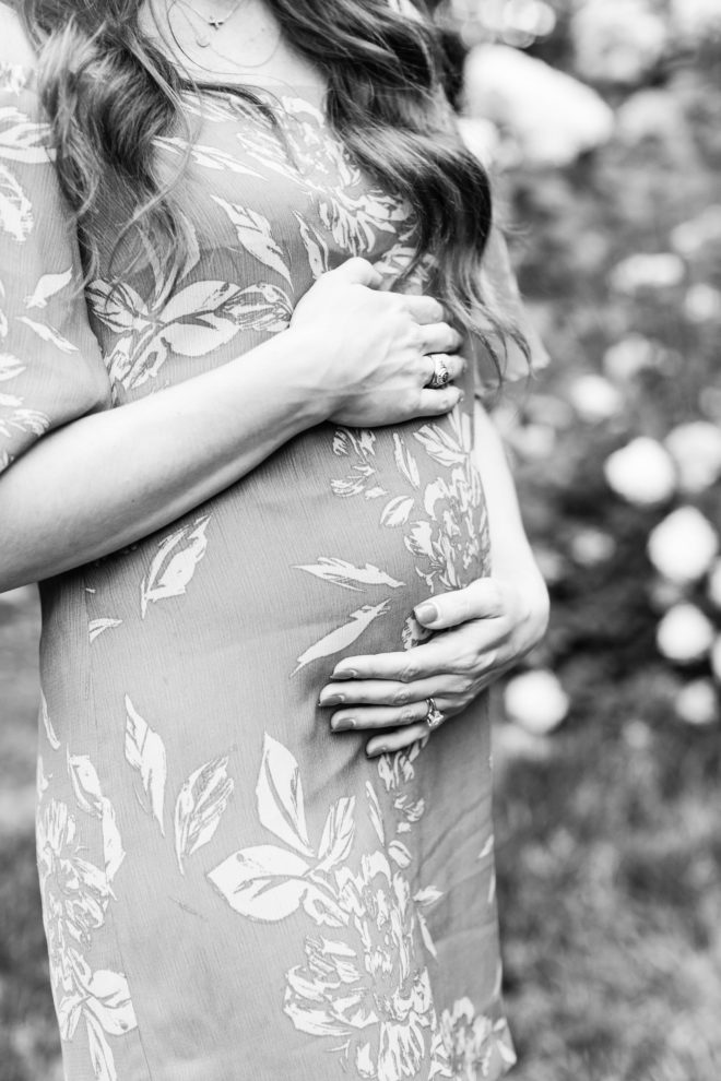 black and white image of a long dark haired women holding her pregnant belly