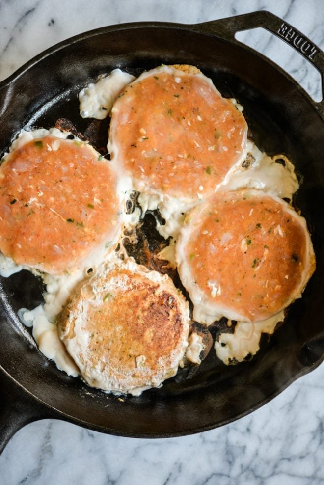 frozen tribali chipotle chicken patties in a cast iron skillet being cooked