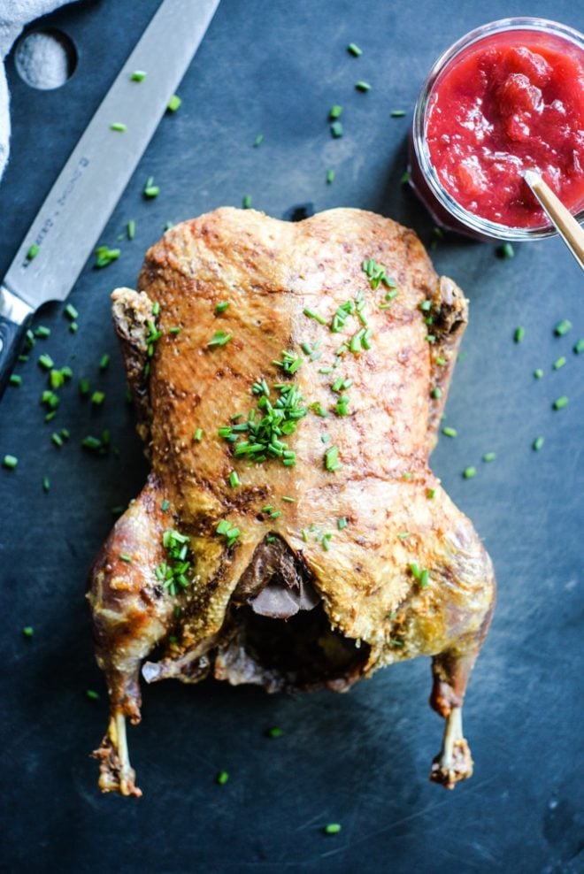 overhead view of easy roasted duck with plum sauce on a black cutting board