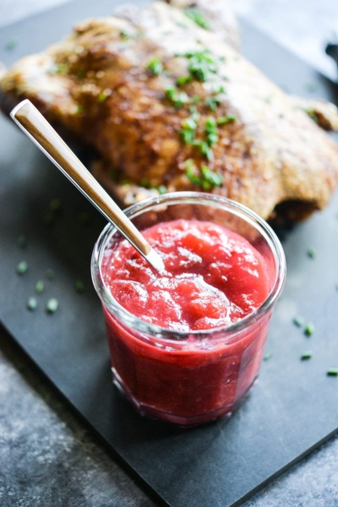 plum sauce in a glass jar with an easy roasted duck blurred in the background