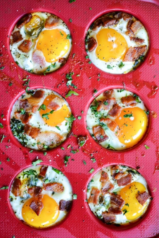 overhead view of balanced breakfast egg cups in a red silicone muffin pan