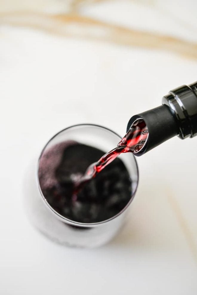 overhead view of a wine bottle pouring natural red wine into a wine glass