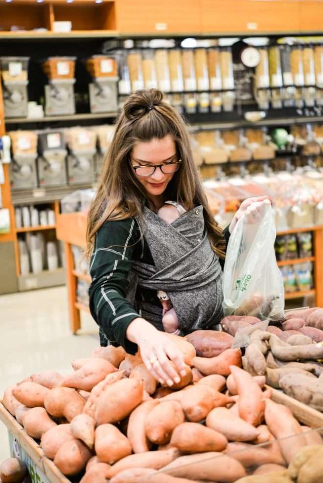 woman wearing a baby and grocery shopping