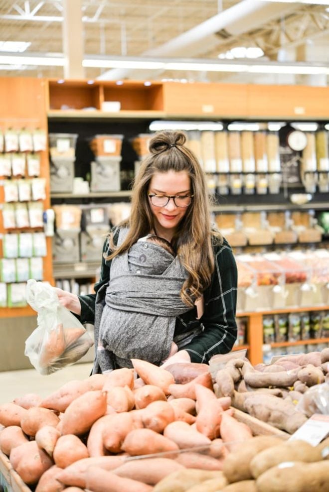 woman wearing a baby and grocery shopping