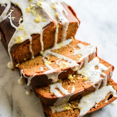 a loaf of Lemon Poppyseed Pound Cake with three slices cut on a marble surface