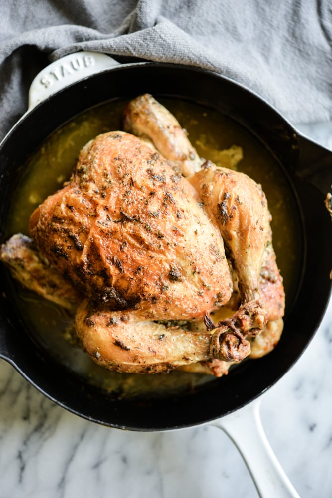 a whole chicken that is cooked and sitting in a cast iron pot 