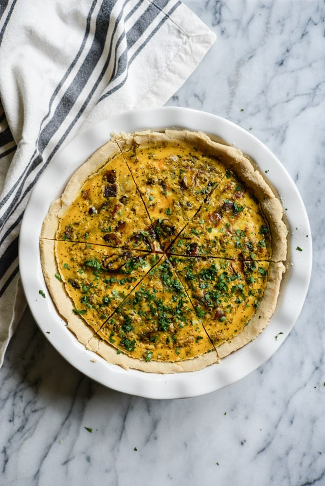 gluten-free quiche in a white pie dish on a marble surface