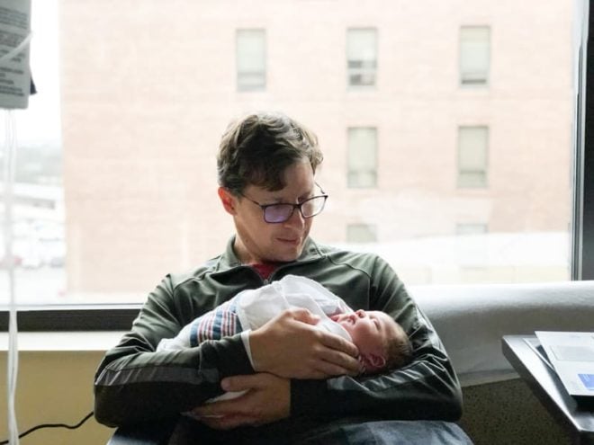 proud father holding swaddled newborn