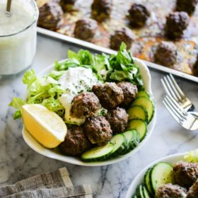 greek meatballs with tzatziki in a white bowl on a marble surface