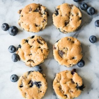 overhead view of blueberry sausage breakfast muffins on a white marbled table with fresh blueberries sprinkled around