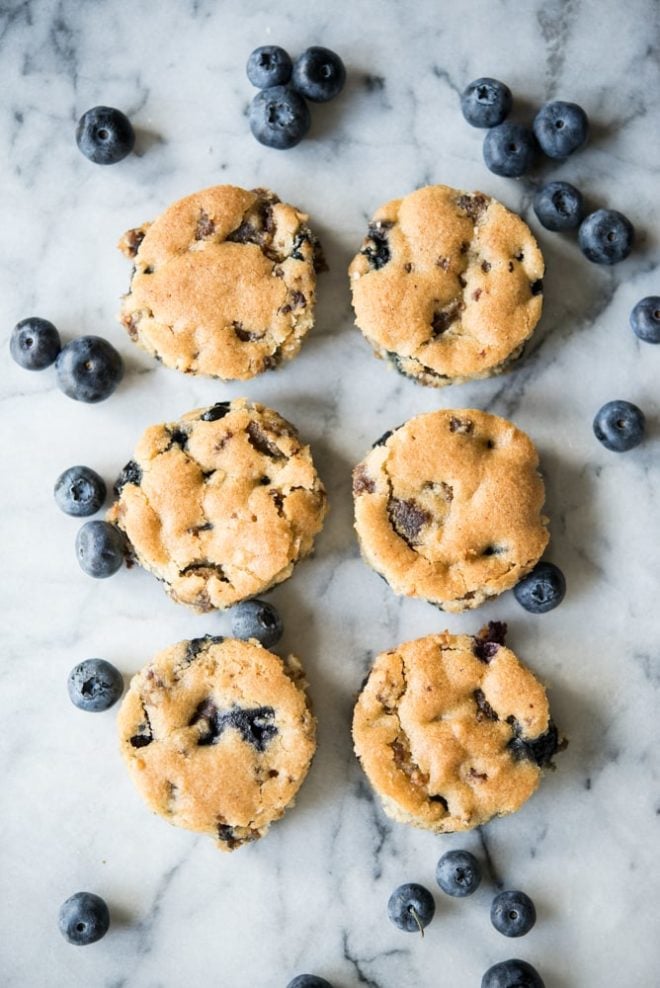 overhead view of blueberry sausage breakfast muffins on a white marbled table with fresh blueberries sprinkled around