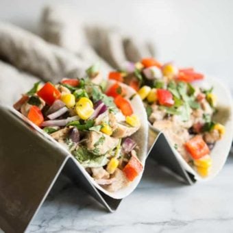 Southwestern Chicken Salad with Jicama Tortillas sitting on a taco stand in front of a tan napkin on a marble surface