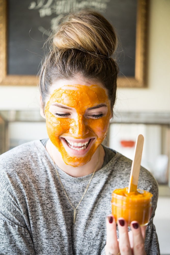 smiling woman with a bun and a DIY pumpkin facial mask on