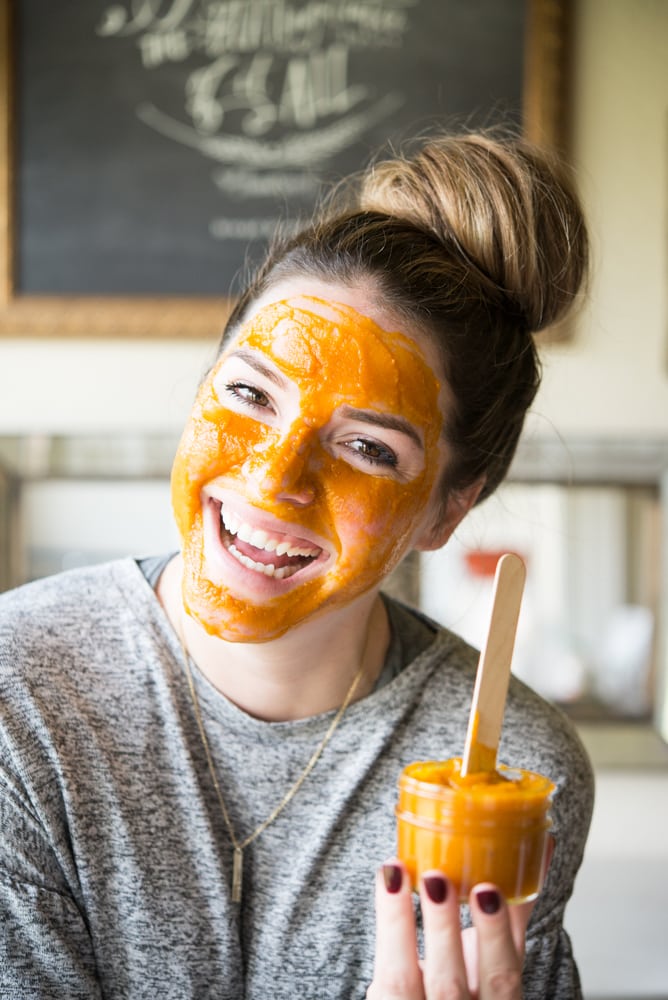 smiling woman with a bun and a DIY pumpkin facial mask on